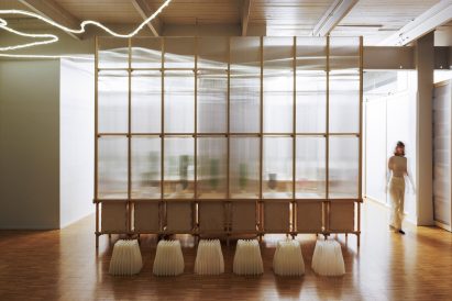 Photo of the algae garden within the Design Apothecary seen from outside the fir wood and polycarbonate panel structure, with lighting glowing through