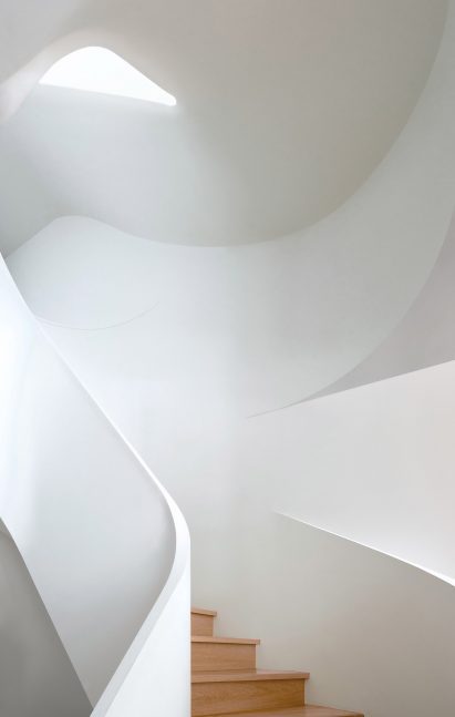 A white sculptural staircase washed in natural light
