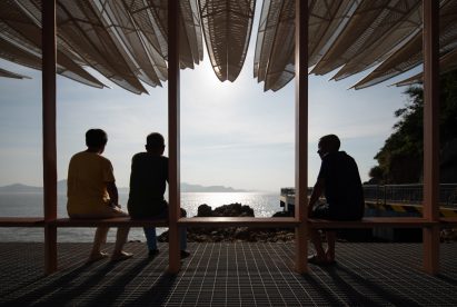 People sitting on bench within The Seaside Pavilion by GN Architects