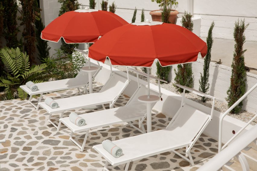 Sun loungers on crazy paving with cypress trees