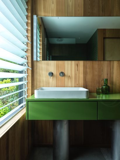 Green formica bathroom vanity supported by stainless steel cylinders