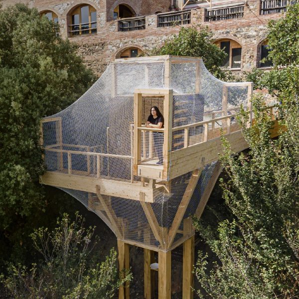 a photograph of a person in a treehouse in tones of beige and white