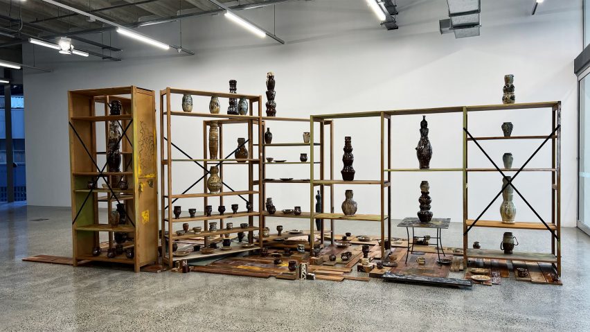 a photograph of an exhibition displaying ceramics on a wooden bookcase