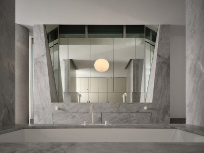 Pale-gray marble and faceted mirrors line a bathroom