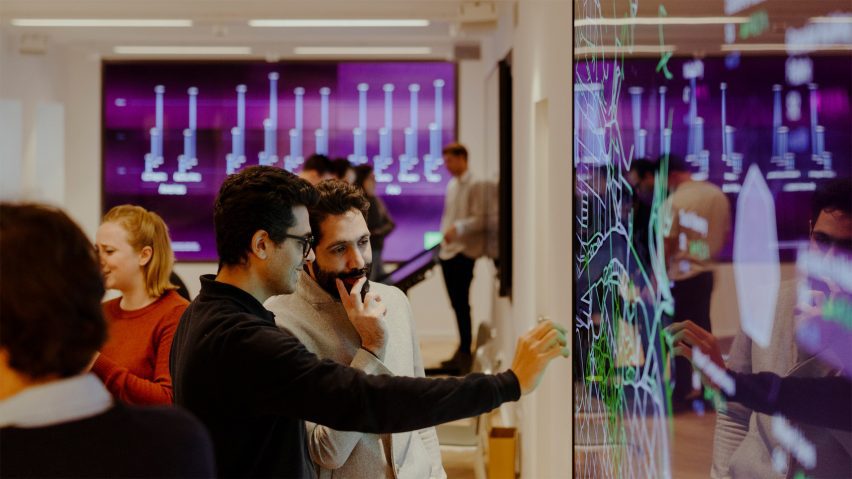 a photograph of people interacting with a purple screen in a room