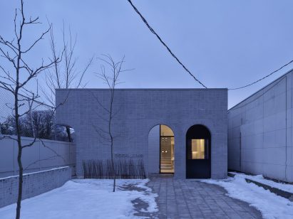 An arcaded grey-brick wall built in front of a former mechanic's workshop