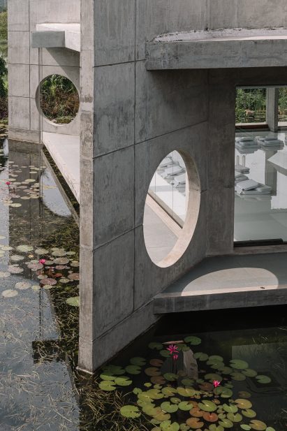 Sculptural concrete building in India surrounded by ponds