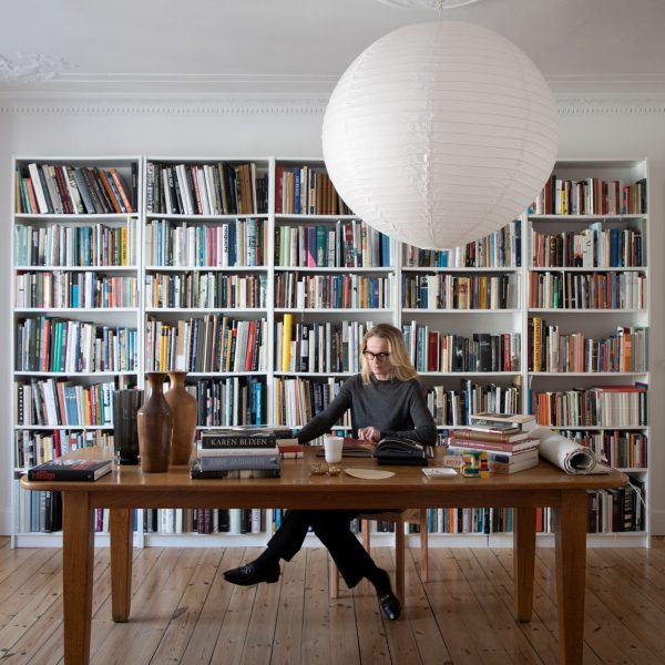 Photo of Marie-Louise Høstbo at a desk in front of bookshelves
