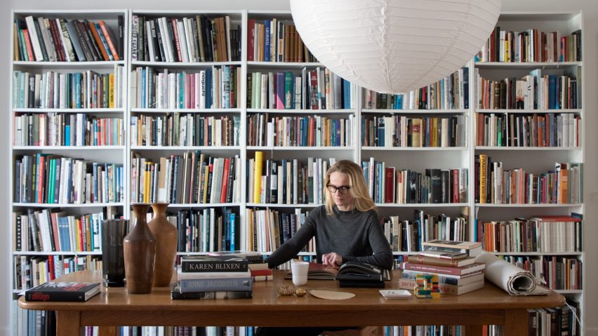 Photo of Marie-Louise Høstbo at a desk in front of bookshelves