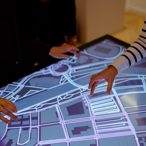 Students placing their hands on an interactive screen showing a map