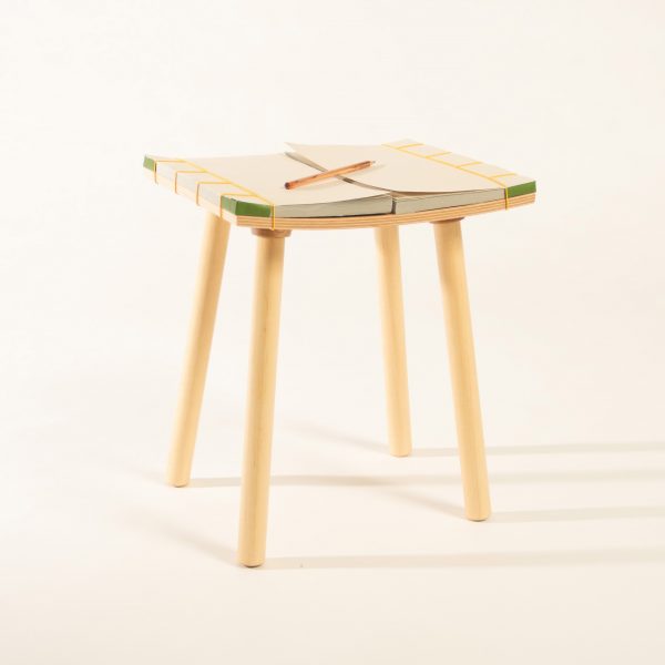 a photograph of a wooden stool with two notebooks as its seat