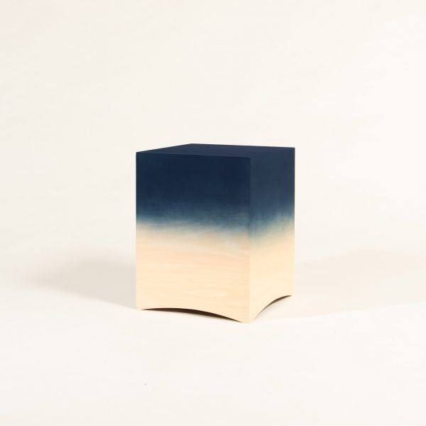 a photograph of a wooden stool in the shape of a cube and in tones of blue and beige