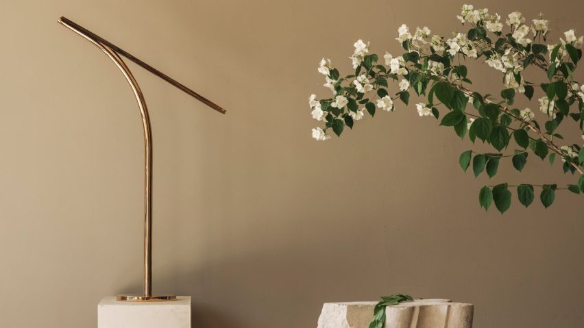 Photo of side table with gold lamp on it and and foliage