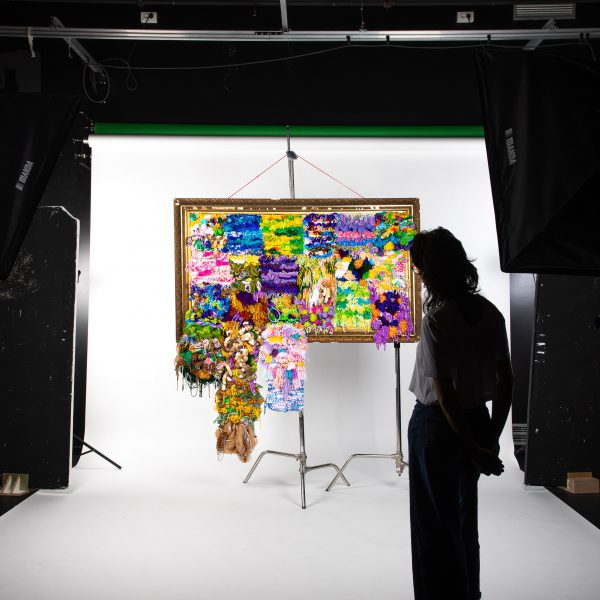 Photo of person stood in front of colourful Unwoven Memories tapestry