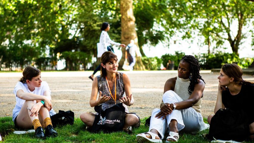 a photograph of students sitting together on a green lawn