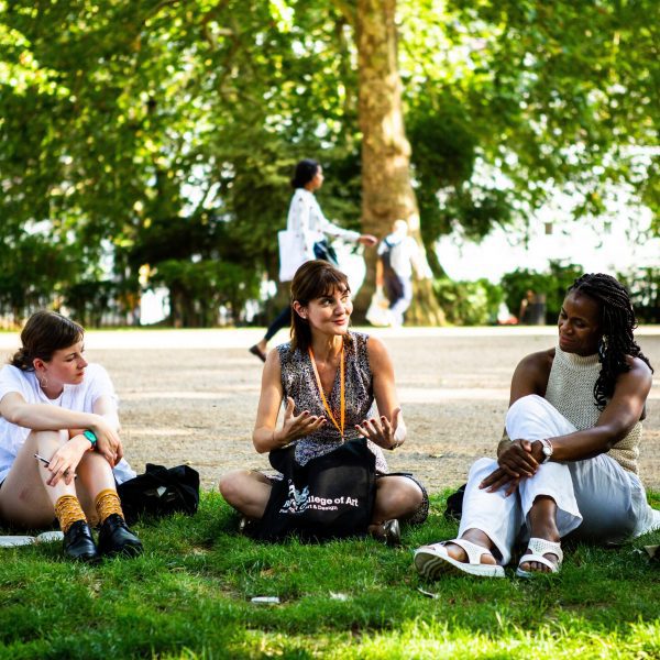 a photograph of students sitting together on a green lawn