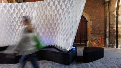 Person walking through St John's Gate archway next to Arthur Mamou-Mani's Harmonic Tides installation
