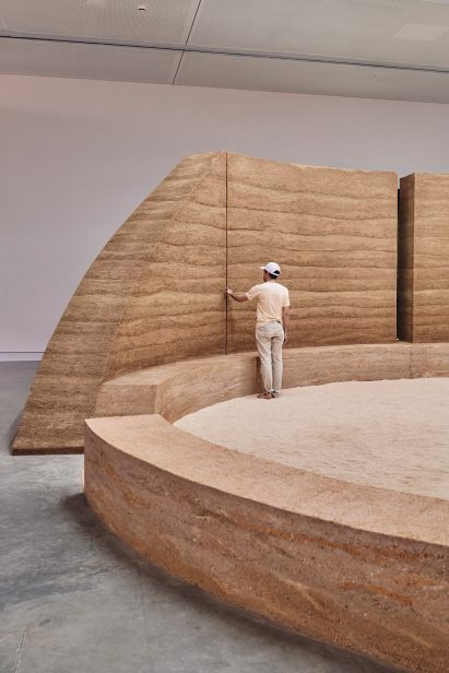 Photo of a rammed earth wall and ring of bench seating with sand in the middle forming a ceremonial ground in the Australia pavilion at the Venice Architecture Biennale 2025