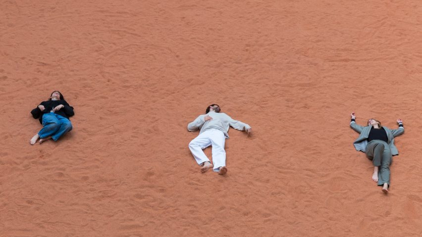 People lying down on red soil of Nobody Owns the Land by Byoung Soo Cho at Palazzo Litta