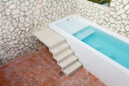 A rooftop swimming pool is entered via a concrete staircase