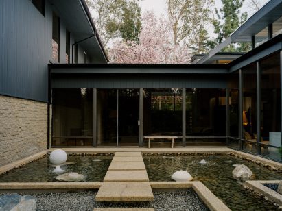 Exterior of modernist house with koi pond and stepping stones leading to entrance