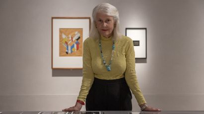 Penelope Seidler standing with hands on exhibition vitrine