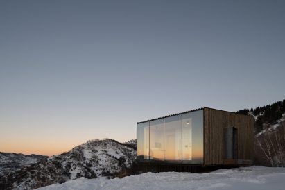 Lit-up wooden cabin in snowy landscape
