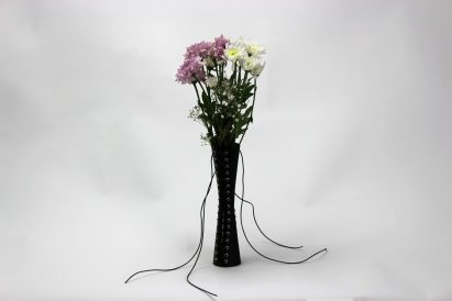 a photograph of a black lace up vase with flowers in it
