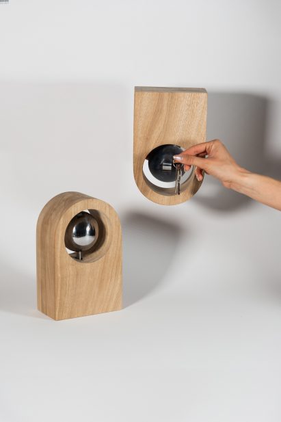 a photograph of two curved wooden objects, and a person's hand holding up a set of keys