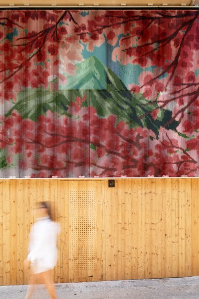 Woman passing by underneath chain curtain emblazoned with landscape painting