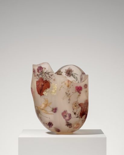 A vessel made from resin and flowers on top of a white pedestal
