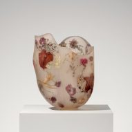 A vessel made from resin and flowers on top of a white pedestal