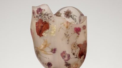 A vessel made from resin and flowers on top of a white pedestal