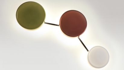 a photograph of three circular wall lights in tones of green, red and white
