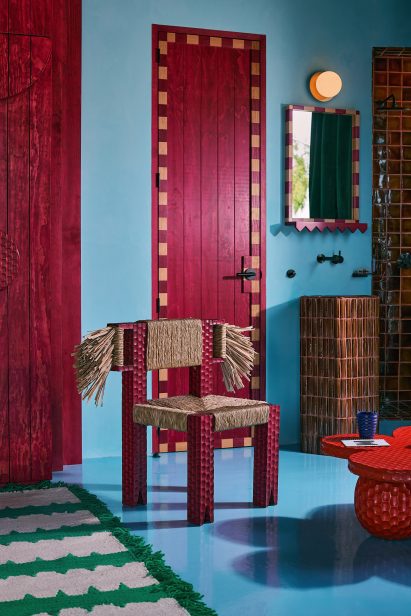 Chair with sisal fringe sides in front of a pink door
