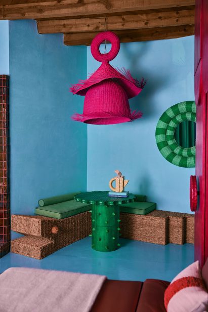 Large pink lampshade hung over a green table and built-in bench