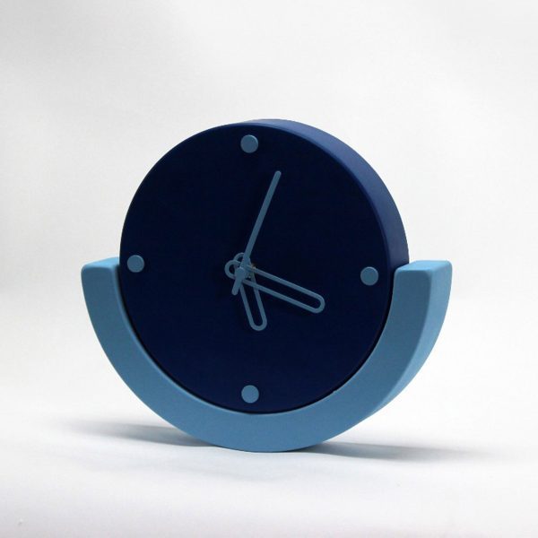 a photograph of an analogue clock in tones of blue against a white backdrop