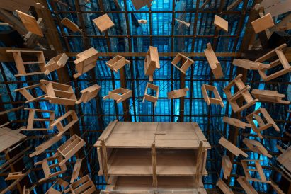 Photo of the ceiling of the Morocco pavilion, showing an installation of many wooden tools and formworks lit from behind with blue light