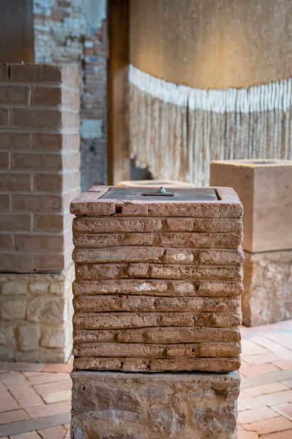 Photo of a pillar in the Morocco pavilion showing sections made of brick and stone and a metal and wooden plate on top