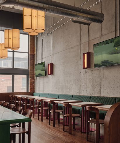 Restaurant in a concrete building with green banquettes and red oak tables