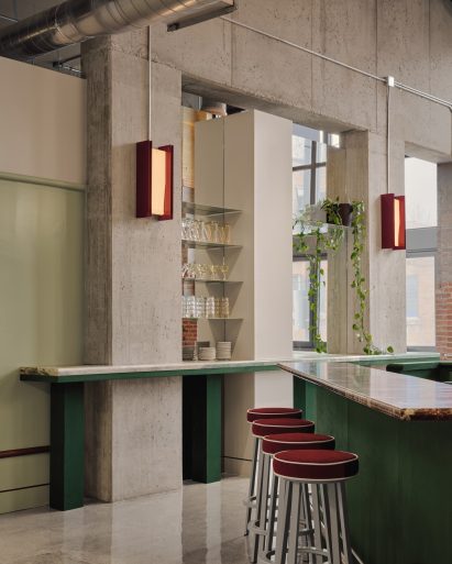 Green and burgundy elements contrast an industrial concrete interior