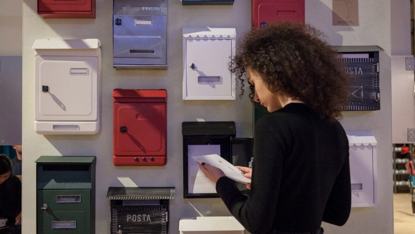 a photograph of a person in front of multiple letterboxes on the wall in tones of red, white, blue and black