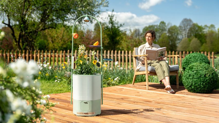 Photo of a woman sitting on a deck in a garden reading a book and looking out over a garden that includes the Wonder Blocks planter