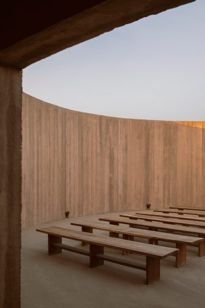 A row of wooden benches within an open-air concrete room