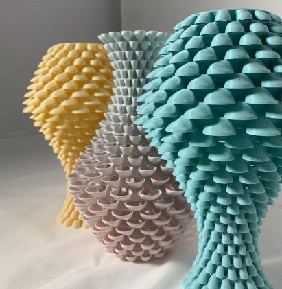 a photograph of three textured sculptures in abstract shapes, in tones of yellow, grey and blue