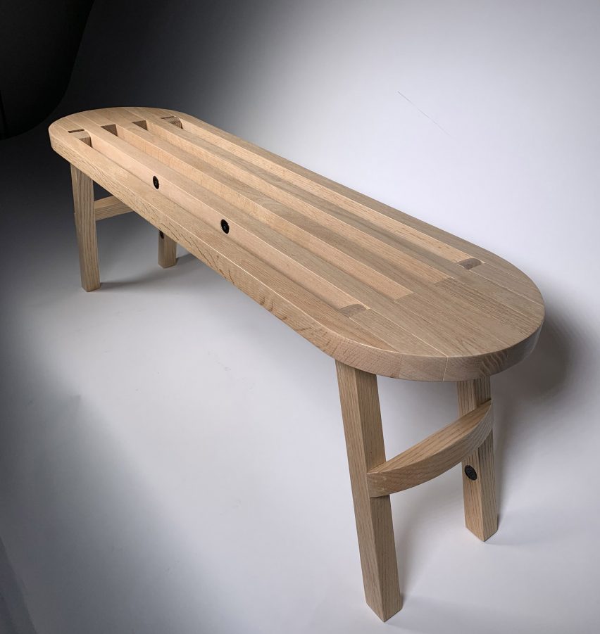 a photograph of a brown wooden bench against a grey backdrop