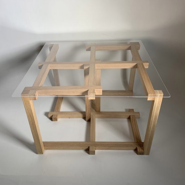 a photograph of a table with a glass top and a geometric wooden base