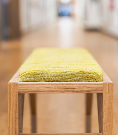 a photograph of a wooden bench with a green cushion on it