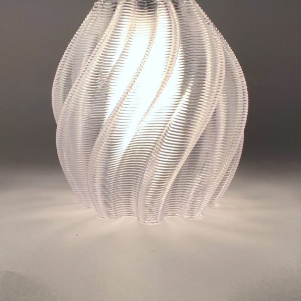 a photograph of a circular transparent lamp, illuminated against a grey backdrop