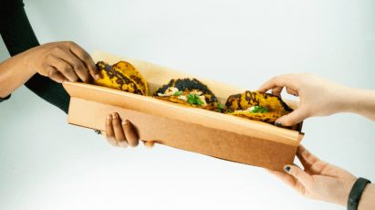 a photograph of people holding food packaging and taking food from it
